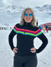 Person wearing a black sweater with colorful stripes in a snowy landscape