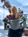 Person wearing a gray sweater with colorful stripes in a snowy outdoor setting