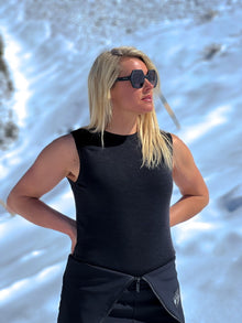  woman wearing black merino vest top in snowy background 