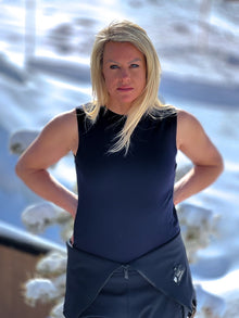  Woman wearing a navy sleeveless top and pants standing outdoors with a blurred natural background