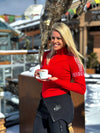 Women wearing a red ski jumper by Snow Finel with patter holding a cup of coffee