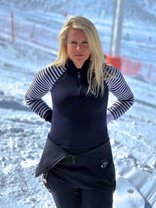  Person wearing a black and white striped shirt with a black vest and pants in a snowy landscape.