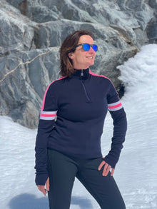  Person wearing a navy blue long-sleeve top with pink accents standing in a snowy landscape.