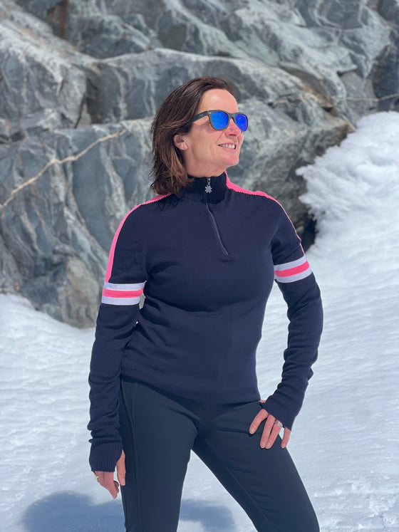 Person wearing a navy blue long-sleeve top with pink accents standing in a snowy landscape.