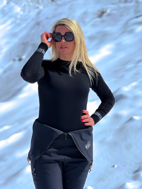 Person wearing a black outfit with a hood in a snowy landscape